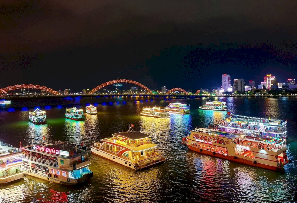 Dozens of cruise ships carry tourists to watch the Dragon Bridge fire show 